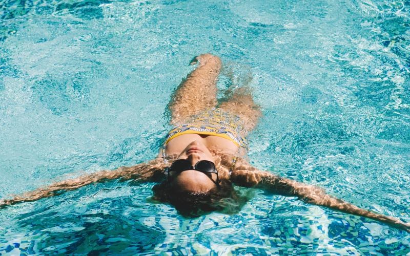 a woman with sunglasses floating on her back in a pool